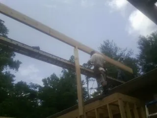 Carpenter setting a ridge beam over a new addition frame — Ice Dam Removal by Roofing Brothers in Pleasant Lake