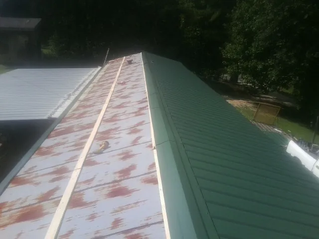 Old rusted panels beside newly installed green metal roofing — Wind Damage Roof Repair by Roofing Brothers in Pleasant Lake